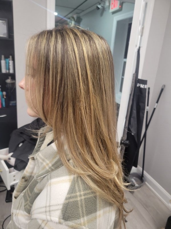 Woman with long straight blonde highlighted hair viewed from behind in a salon setting